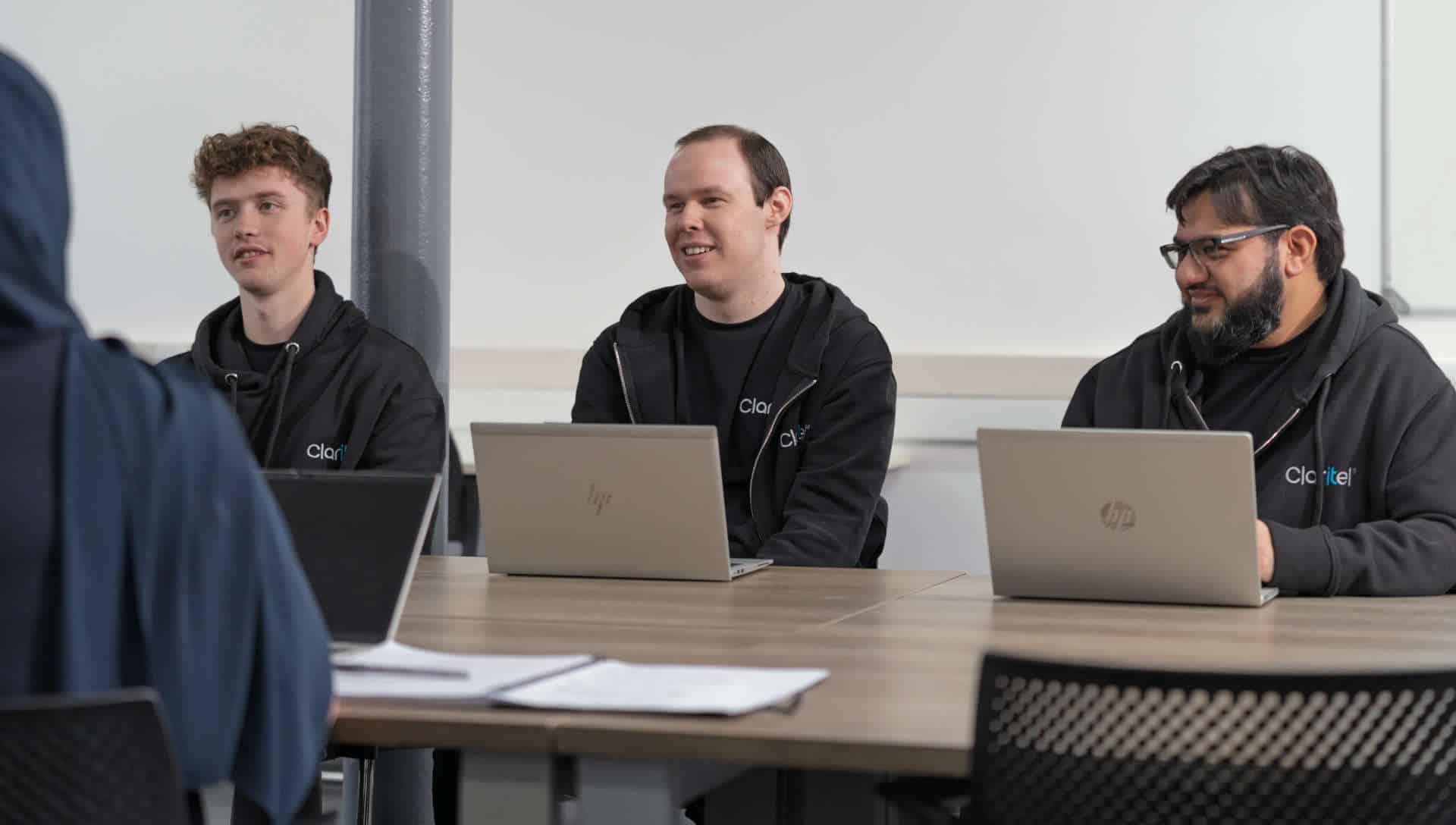 Members of the Claritel team sat round a table with laptops